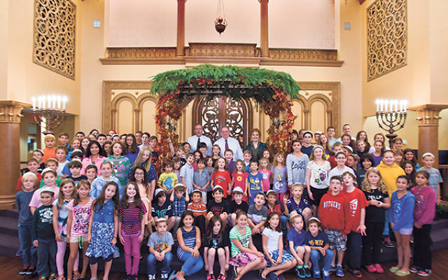 In the sanctuary, Rabbi Bennett Miller, rear, center, gathers with fellow Anshe Emeth Memorial Temple clergy, Rabbi Philip Bazeley and Cantor Anna West Ott, and a crowd of the congregation’s children.     