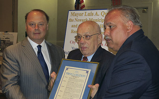 Holocaust survivor Theodore Halpern, center, receives a proclamation from Newark builder Miles Berger, left, and Mayor Luis Quintana.     