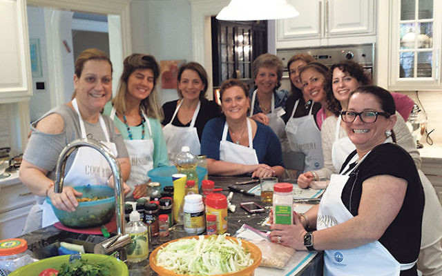Osi Lankri and her assistant Mor Bohadana, left, create an Israeli meal in a Short Hills home; with them are, from left, host Robin Buchalter, Beth Levin, Eileen Breindel, Catalina Silberman, Philippa Miller, Stephanie Evenchick, and Debbie Zucker.