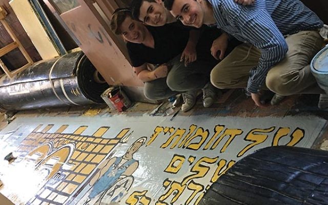 Yoni Leykin, Max Greenberg, and Noah Hanover, seniors at the Jewish Educational Center’s Rav Teitz Mesivta Academy, work on their school banner for the Celebrate Israel Parade. Courtesy JEC