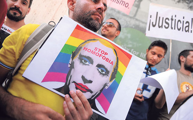 A man holds a sketch showing Russian President Vladimir Putin wearing lipstick during a protest against Russian anti-gay laws outside the Russian embassy in Madrid, Aug. 23, 2013.        