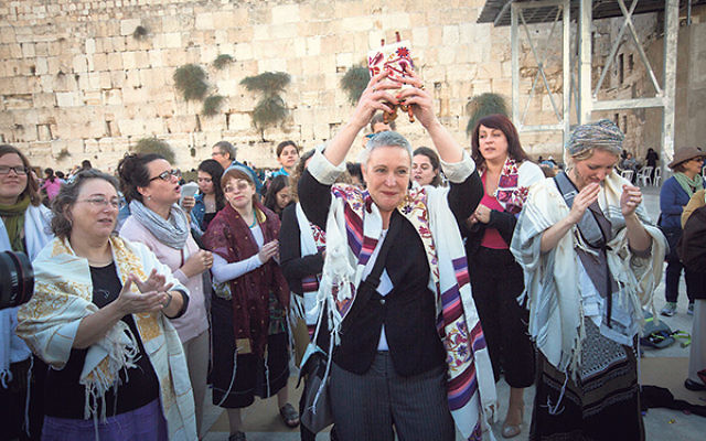 Lesley Sachs holds aloft a tiny Torah scroll during a Women of the Wall service at the Kotel.     