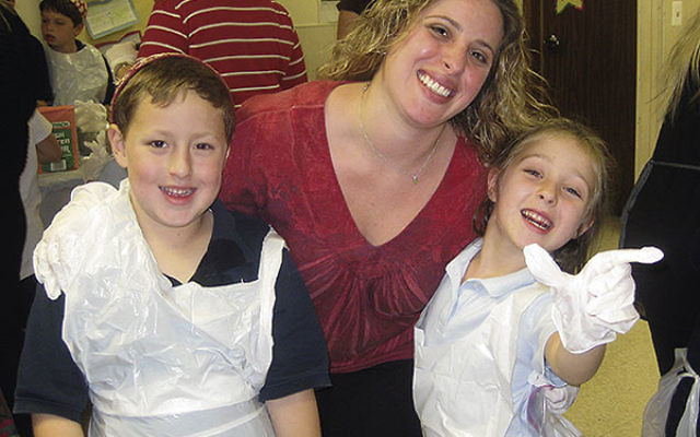 Shiri Arroyo and her children, Izzy and Maytal, former students at the Raritan Valley Solomon Schechter Day School, get into a family halla-baking event at their new school, SSDS of Greater Monmouth County.