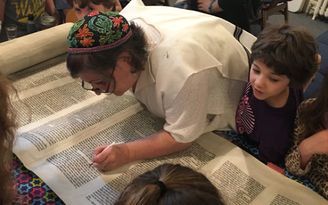 Soferet Linda Coppleson shows religious school students how she repairs a letter.