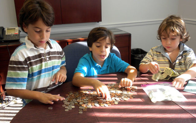 Lee Brewster, center, counts the money he collected for the poor, helped by his brothers, Ryan, left, and William, at the Central federation.
