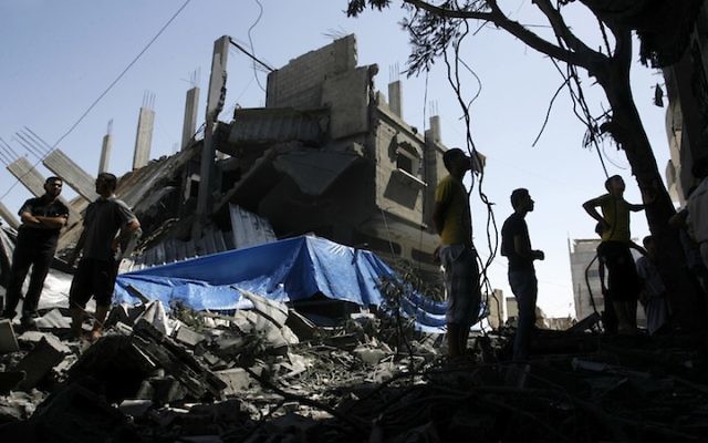 Palestinians walking among the rubble of a destroyed house following an Israeli missile strike, in Rafah, in the southern Gaza Strip, July 14, 2014. (Abed Rahim Khatib/Flash 90)