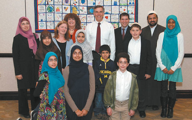Jewish, Christian, and Muslim children gather around the interfaith quilt for which they designed squares. With them are, from left, rear, Fatima Jaffari, the Rev. Myrna Bethke, Toby Shylit Mack, Rep. Rush Holt, Rabbi Aaron Schonbrun, and Imam Mehdi.