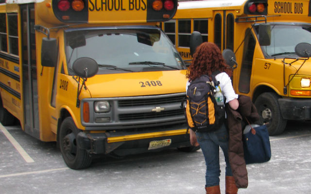 A student at Solomon Schechter Day School of Essex and Union in West Orange heads for a school bus in the parking lot. State transportation aid to families of parochial school students has been spared from state budget cuts.