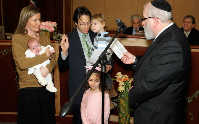 Rabbi Shlomo Krupka of Congregation Etz Chaim administers the oath of office to Michael Rieber, who is joined by his family, wife Sarah holding Sasha, Emma, and Jonah. Photos by Bob Krasner