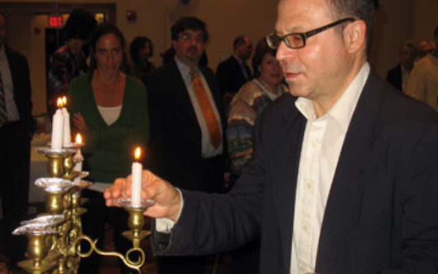 Jonathan Rothchild, a member of Oheb Shalom and a client at JESPY House, lit a candle on the menora at the JESPY-Oheb Shalom Hanukka party held the fifth night of the holiday.