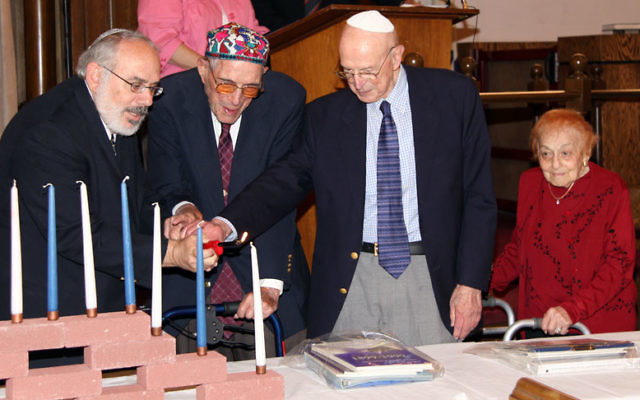 Rabbi David Nesson, left, lights candles with three of the congregation’s oldest members, from left, Harold Krauss, Herman Frigand, and Rookie Friedman. Photo courtesy MJCBY