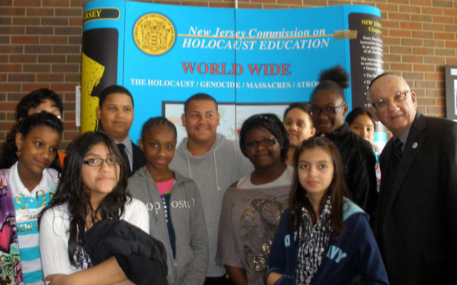 Dr. Paul Winkler, executive director of the NJ Commission on Holocaust Education, joins students from the William C. McGinnis School in Perth Amboy at an exhibit of student work about the Holocaust on display before the start of the Yom Hashoa program at