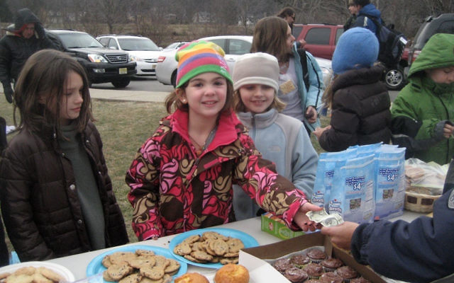 Madison Schuckman, eight, in striped hat, completes a transaction at the bake sale she held at Wildwood Elementary School in Mountain Lakes on Dec. 16 to raise funds for victims of the Carmel Forest fire. Photo courtesy Schuckman family