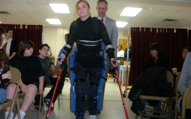 Agnes Fejerdy, who was left a paraplegic after a car accident more than six years ago, demonstrates to students and staff at the Solomon Schechter Day School of Greater Monmouth County how she walks with the aid of the ReWalk. Behind her is Thomas C. Coul