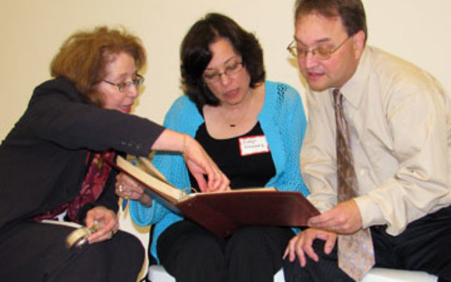 Monica Hartman, left, and siblings Evelyn Altenberg and Les Altenberg, children of Holocaust survivors who found refuge in Latin America, look at a photo album of survivors in the Dominican Republic.