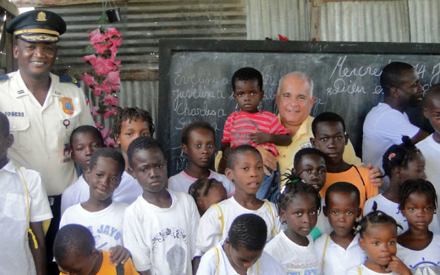 Alan Goldsmith, president of the Jewish Renaissance Medical Center and Foundation, is surrounded by children at the Tabarre School near Port-au-Prince, which the foundation has adopted. With them is national police commissioner Justin Marc, far left. Ph