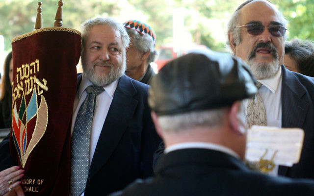 Robert Pearson, left, carries the Torah scroll into the synagogue as Rabbi Daniel Grossman, right, and clarinetist Steven Kaplan proceed into the synagogue for the dedication.
