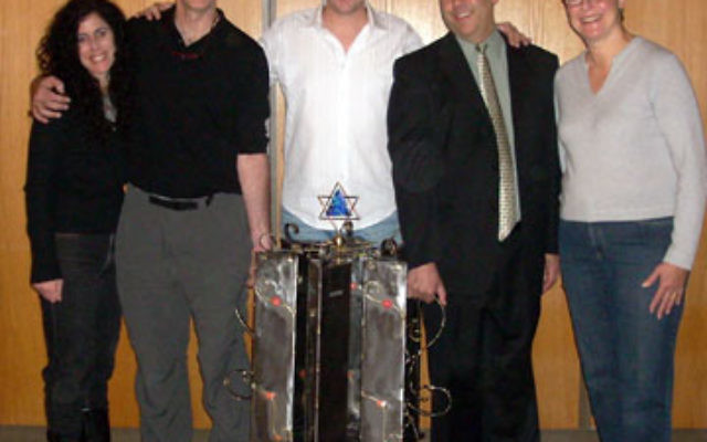 Gary Rosenthal, second from left, designed the tzedaka box to mark The Jewish Center’s 60th anniversary. With him are, from left, Naomi Perlman, 60th anniversary committee chair; Neil Wise, director of programming; Rabbi Adam Feldman; and H