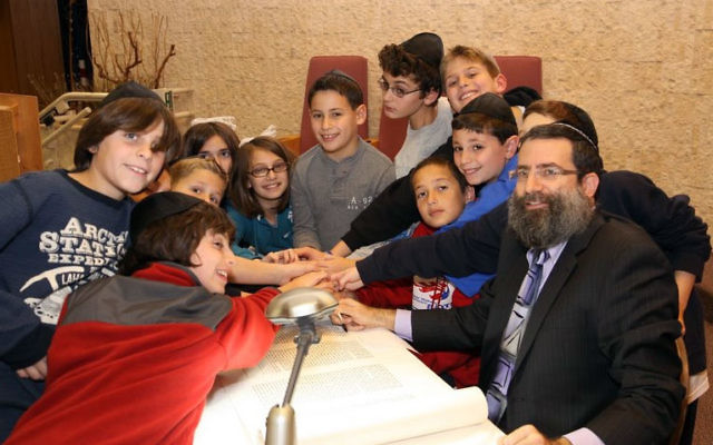 Children gather around sofer Moshe Druin as he inscribes letters in the Torah scroll, which is now housed in Congregation Shir Ami’s chapel.