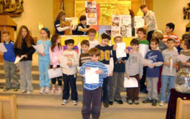 Students at the Solomon Schechter Day School of Raritan Valley in East Brunswick affix photos and words to a hanukkia during the Terrific Thursday program, which raised close to $500 for the Jewish Federation of Greater Middlesex County. Photos