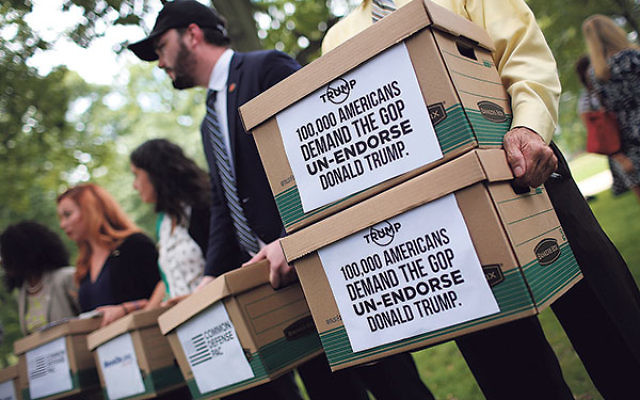 Former members of the U.S. military carrying boxes with more than 100,000 signatures requesting that Sen. John McCain and other Republican leaders withdraw their endorsement of Republican presidential candidate Donald Trump following a press conference in