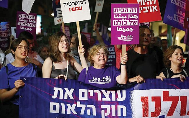 A protest against the “Jewish Nation-State Bill” in Tel Aviv on July 14. The pink sign reads in Arabic and Hebrew, “This is the home of all of us.” (Jack Guez/ AFP/Getty Images)