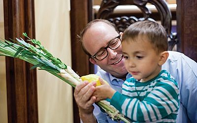 Rabbi Philip Bazeley of Anshe Emeth Memorial Temple explains the significance
of the etrog and lulav to a young congregant. Photo by Ouriel Morgansztern