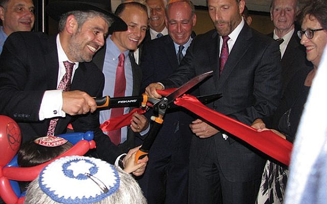 Rabbi Mendel Solomon cuts the ribbon held by Livingston Council Member Michael M. Silverman, second from right, and others. Photo by Johanna Ginsberg