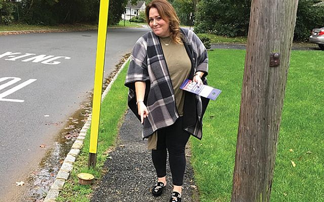 Livingston Town Council candidate Debbie Burack points to one of the many damaged sidewalks she hears residents complain about. Photos by Johanna Ginsberg