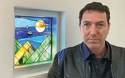 Designer Lev Gal Wertman stands beside the window depicting the creation of the sun, moon, and stars at Gottesman RTW Academy. Photos by Johanna Ginsberg