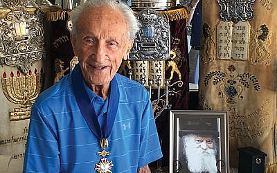 Ed Mosberg, wearing his Polish Order of Merit with a part of his collection of Holocaust memorabilia.