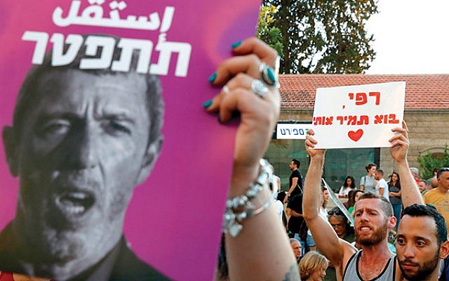 Members of the LGBT community hold a banner reading in Hebrew “a homophobic racist has to quit” during a July 14 rally in Tel Aviv against Israel’s Education Minister Rafi Peretz (portrait) following his remarks on gay conversion therapy. JACK GUEZ/AFP/Getty Images