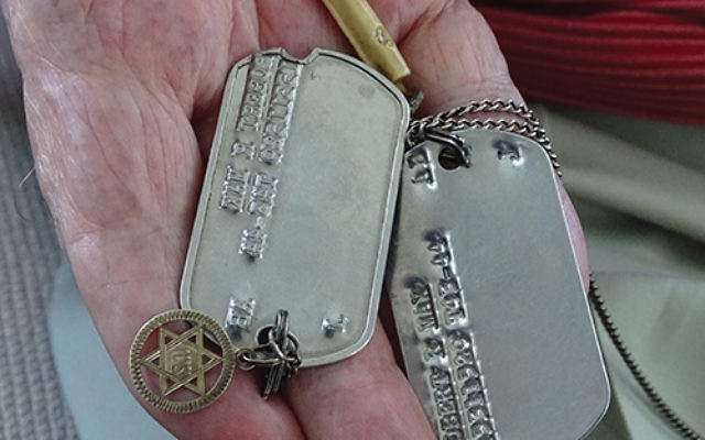 Bob Max holds the Army dog tags, with a star of David and mezuzah attached, that went unnoticed by his Nazi captives in World War II. Photos by Robert Wiener