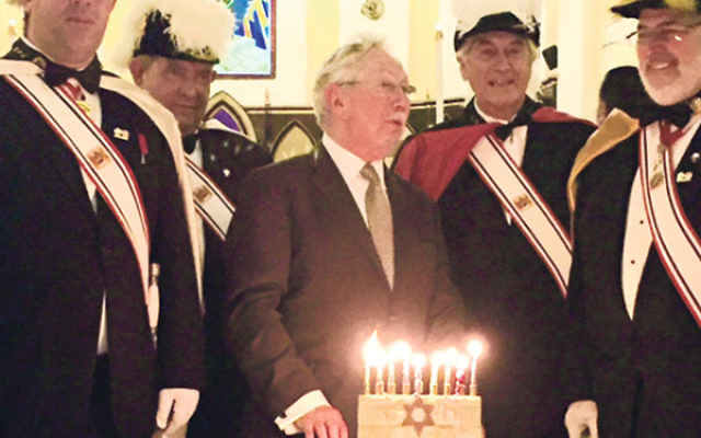 Rabbi Norman Patz lights the menora surrounded by members of the Knights of Columbus.