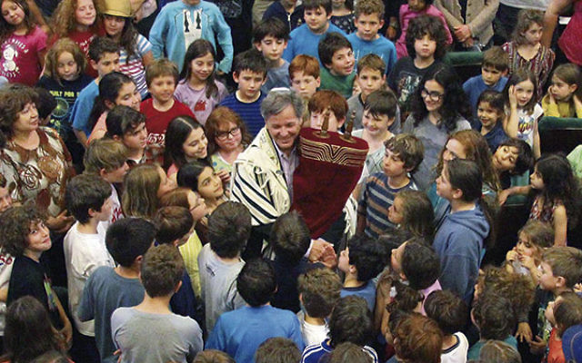 Rabbi John Rosove celebrates with the “Torateinu ARZA” scroll among students at Temple Israel of Holywood Day School in Los Angeles. The scroll will be at three NJ Reform synagogues May 30-June 4 before being donated to a Reform congregation i