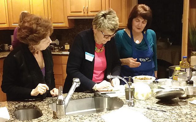 Yvette Schlussel, right, guides Beth Hoffman on the proper technique for making healthy quinoa-filled stuffed cabbage as Vera Galleid looks on at a recent Hadassah cooking demonstration.