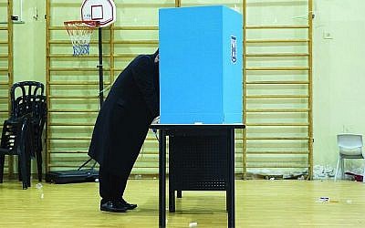 A charedi Orthodox man stands behind a voting booth before casting his ballot Tuesday in Israel’s general elections in Bnei Brak. Getty Images
