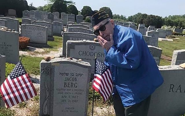 During a previous Memorial Day weekend, Louis Raiman places flags on the grave of Jewish war veteran Jacob Berg at Mount Lebanon Cemetery in Woodbridge. 
Photo courtesy Sonja Erdelyi