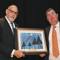 Rabbi Mark Karasick, chairman of the board of the Sinai Schools, presents a student-made gift to honoree Micah Kaufman.