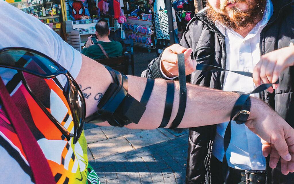 A Chabad emissary helps a man wrap tefillin on Allenby Street in  Tel Aviv. (Amir Appel/Flickr Commons)