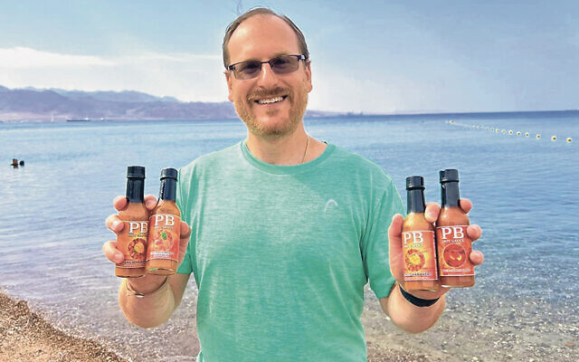 Perry Bindelglass holds his PB Hot Sauce near the Red Sea on the Gulf of Aqaba in Eilat, Israel, on a recent family trip. (Perry Bindelglass)