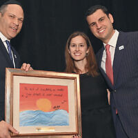 Sinai Schools’ President Avi Vogel, left, presents a student-made work of art to honorees Erica and Tzvi Solomon.