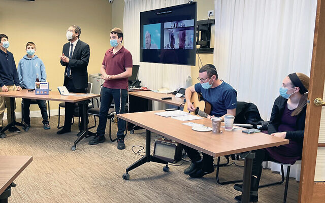 Rabbi Raphael Karlin with JEC students, left, conducts the seder with guitarist Seth Huttel and his wife, Rivki Huttel. (Courtesy JFSCNJ)
