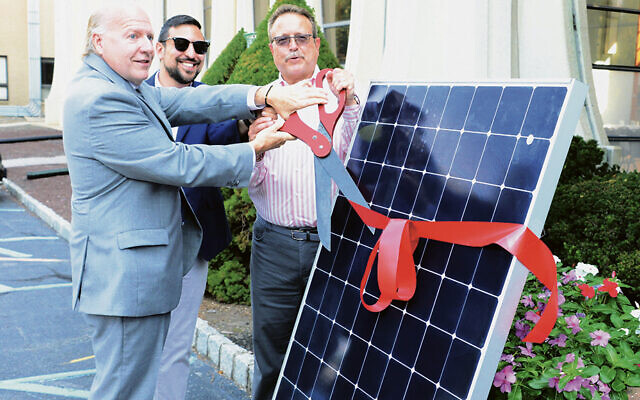 From left, Livingston Mayor Michael Vieira, Rabbi Simeon Cohen of Temple Beth Shalom of Livingston, and Brian Fern, the shul’s executive vice president, cut the ribbon on September 7, as the synagogue’s solar panel system was dedicated. Mr. Fern chaired a shul committee that worked for years to finish the solar panel project, which was delayed by the pandemic. (Jerry Siskind)