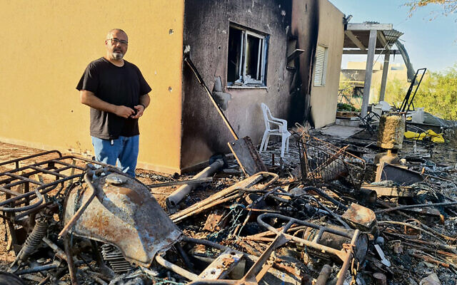 Former Kfar Aza resident Gili Okev sits outside his ruined house, a month after Hamas terrorists invaded and killed many of his neighbors. (Deborah Danan)
