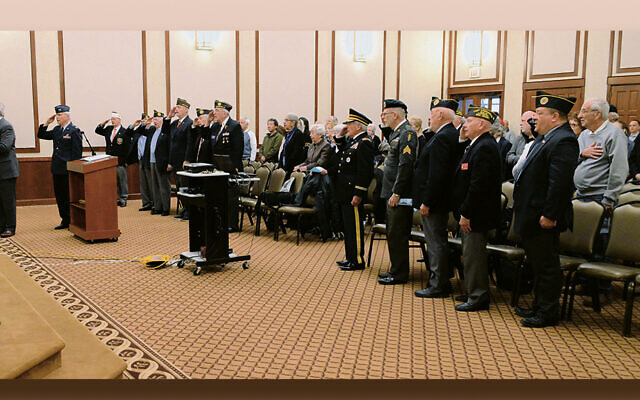 Veterans salute as Cantor Perry Fine, left, of TBS, sings the national anthem.(Jerry Siskind)