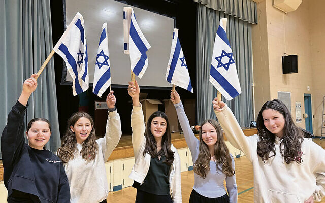 Eighth-graders at the Solomon Schechter School of Bergen County in New Milford hold up Israeli flags.