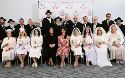 Rabbi Mordechai Kanelsky, center is flanked by Eduard Slinin, to his right, and Yanky Bennish, the Young Leadership awardee, to his left. Rebbetzin Shterney Kanelsky is seated center; Chaya Bennish is on her left. Brides and grooms surround them. (Courtesy Bris Avrohom)
