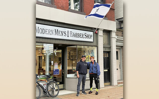 Dave Drovandi, with the cross, and Jeff Stark, in the helmet, stand together outside Modern Men’s Barber Shop in Madison.