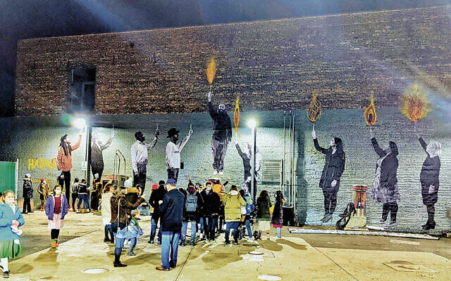 This take on a menorah, painted on a wall in Brooklyn, uses local people as images of light-givers. (All photos courtesy Raabi Yizchok Moully)